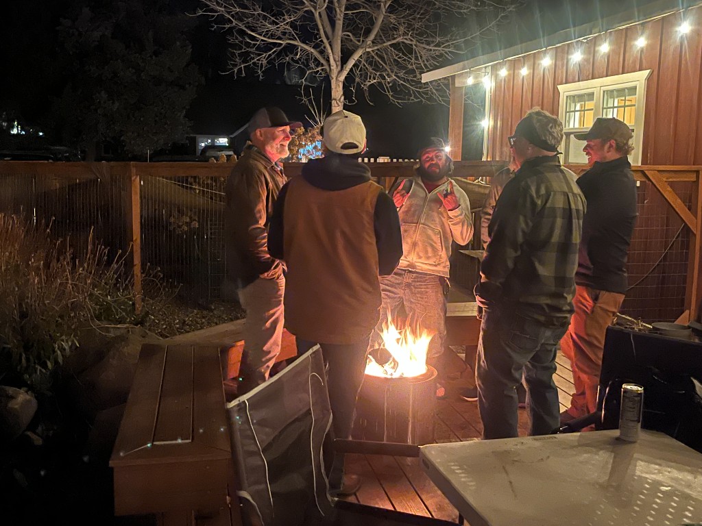 Men gathered around a fire pit on a Saturday evening